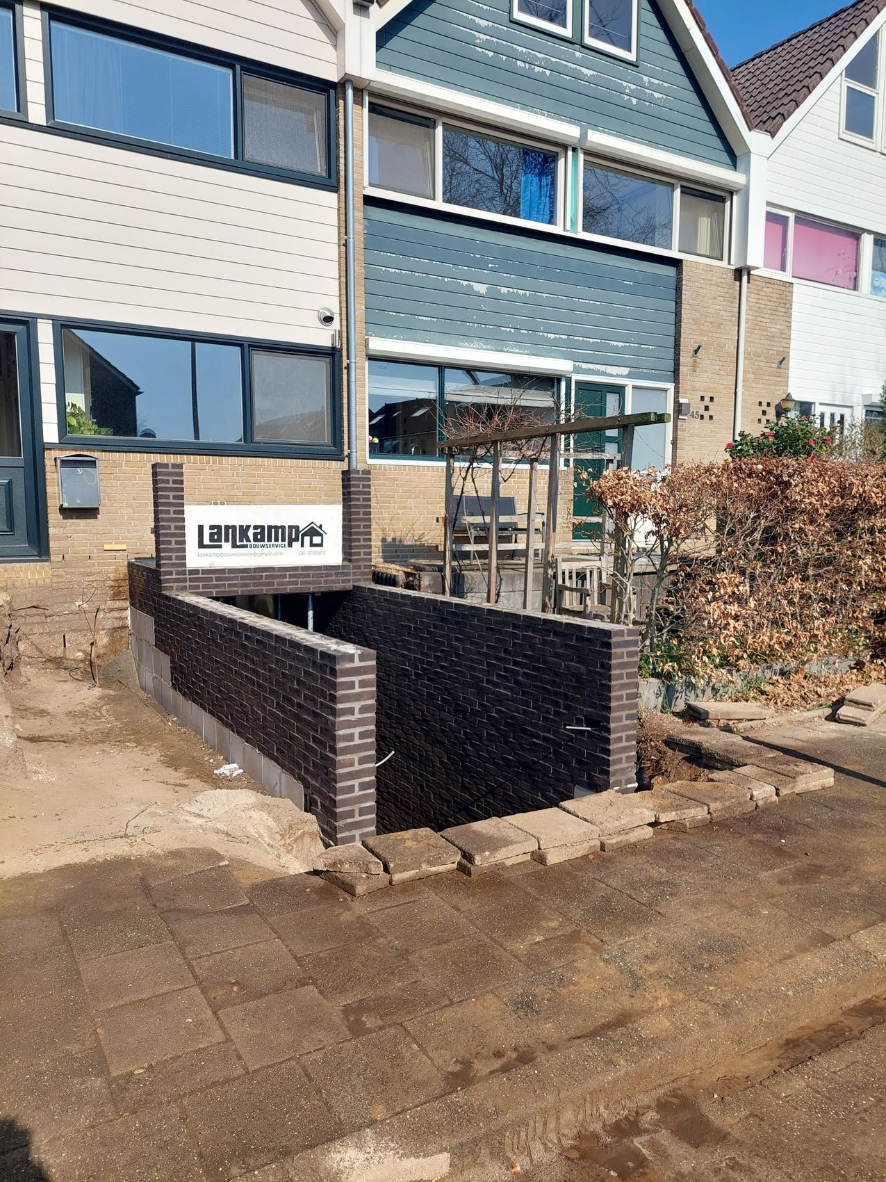 Nieuwe keerwand van donkere bakstenen bij een woning